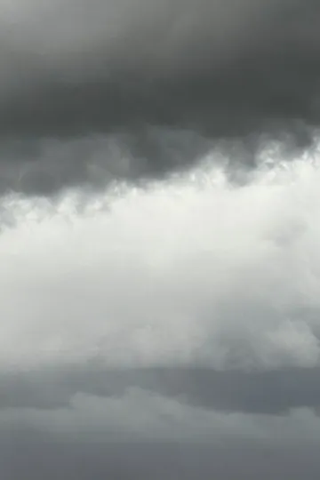 A brooding, overcast sky—a dark band of storm clouds giving way to a paler expanse of light below.