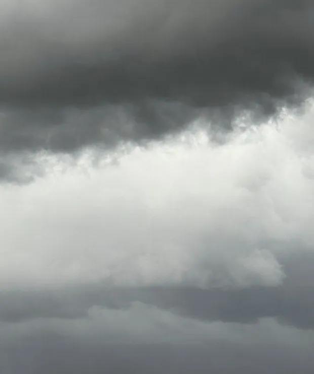 A brooding, overcast sky—a dark band of storm clouds giving way to a paler expanse of light below.
