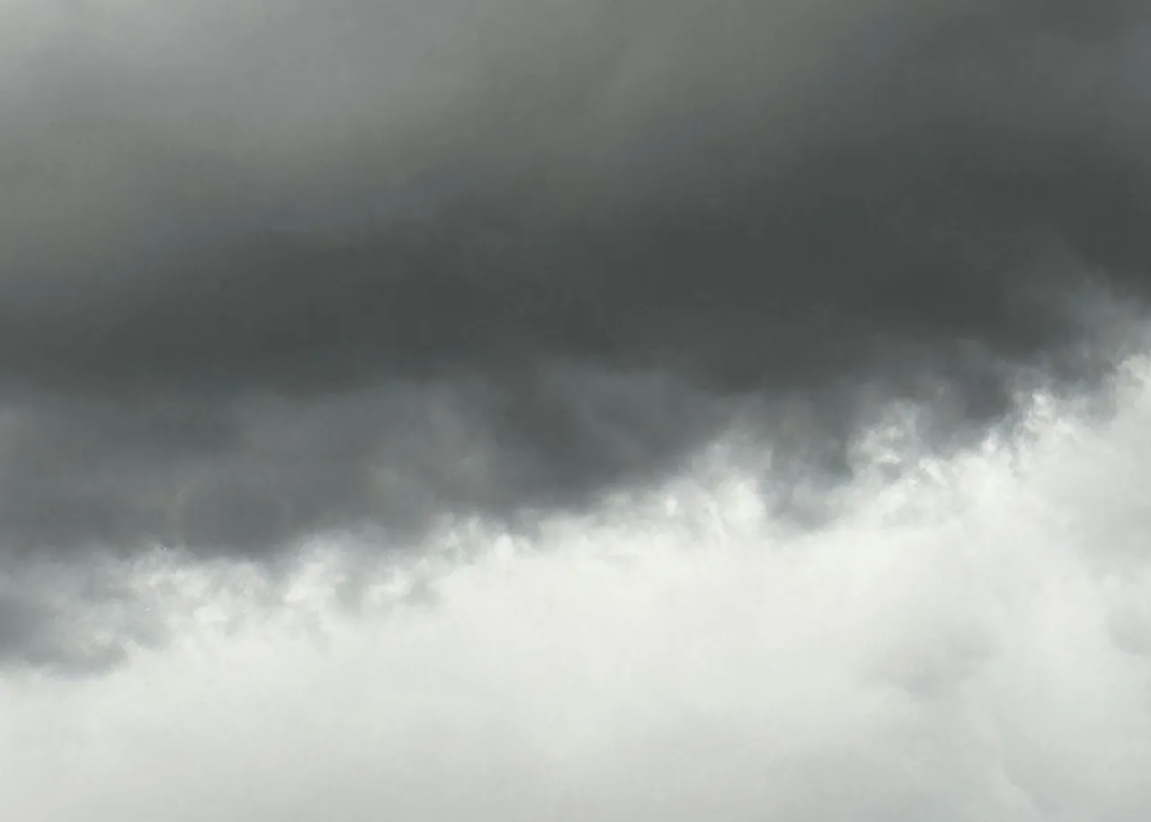 A brooding, overcast sky—a dark band of storm clouds giving way to a paler expanse of light below.