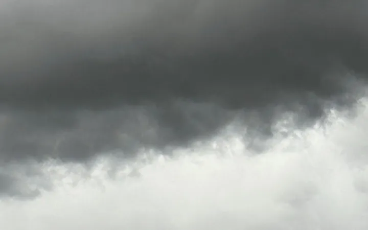 A brooding, overcast sky—a dark band of storm clouds giving way to a paler expanse of light below.